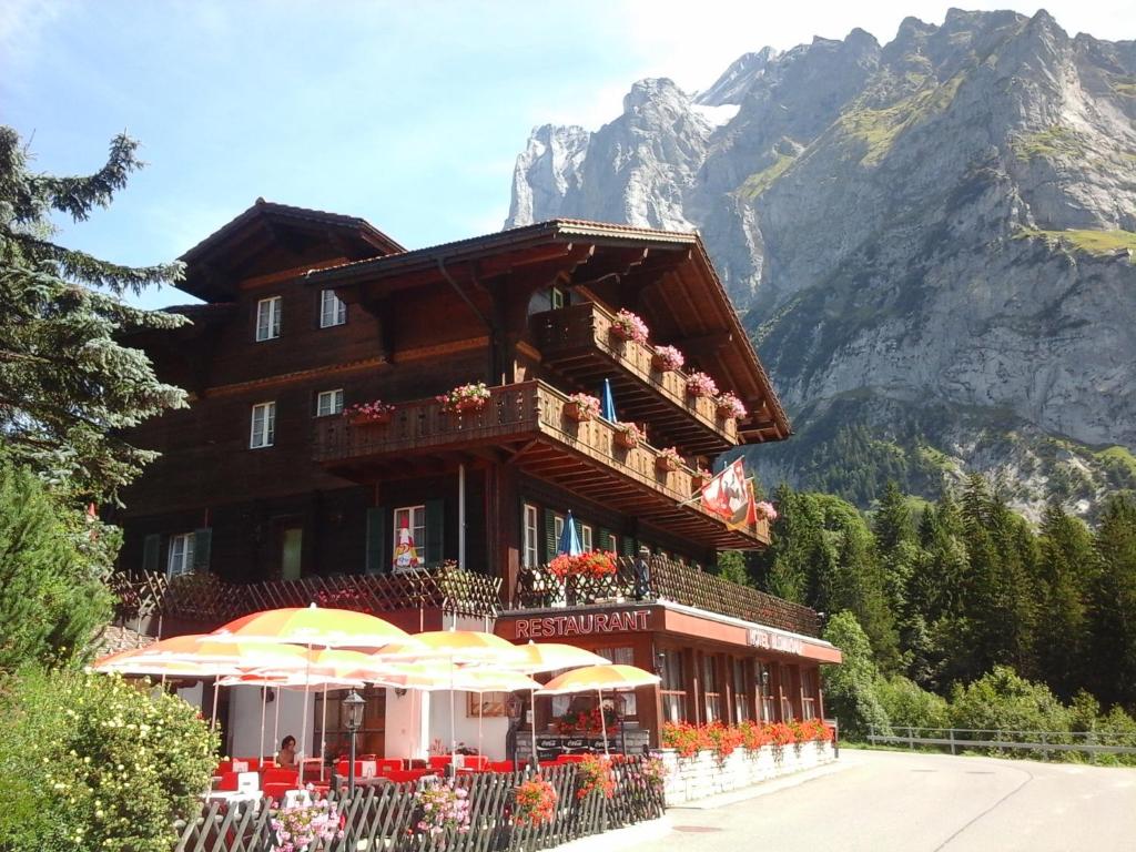 ein Gebäude mit Tischen und Sonnenschirmen davor in der Unterkunft Hotel Blümlisalp in Grindelwald