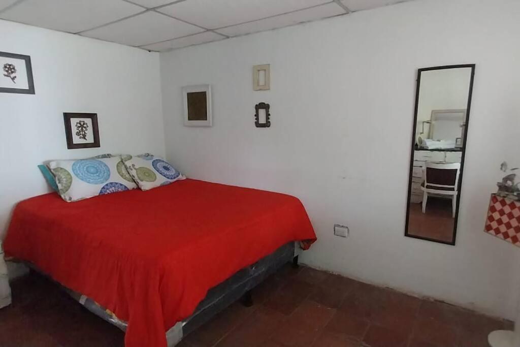 1 dormitorio con cama roja y espejo en Jardín Paraíso en Amatitlán