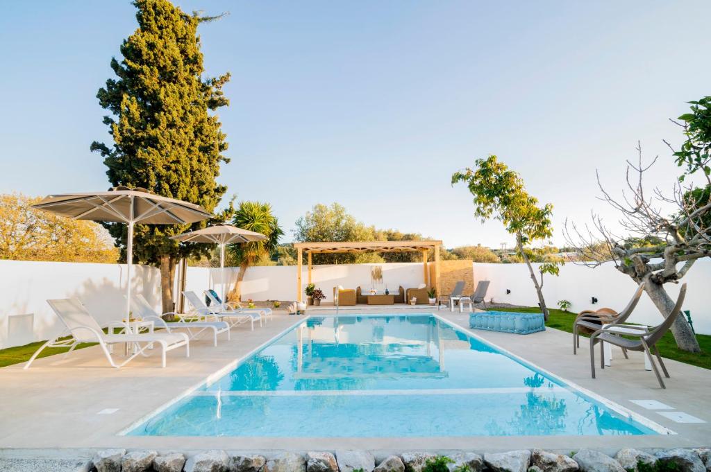 a swimming pool with chairs and an umbrella at Villa Eleni in Soroni