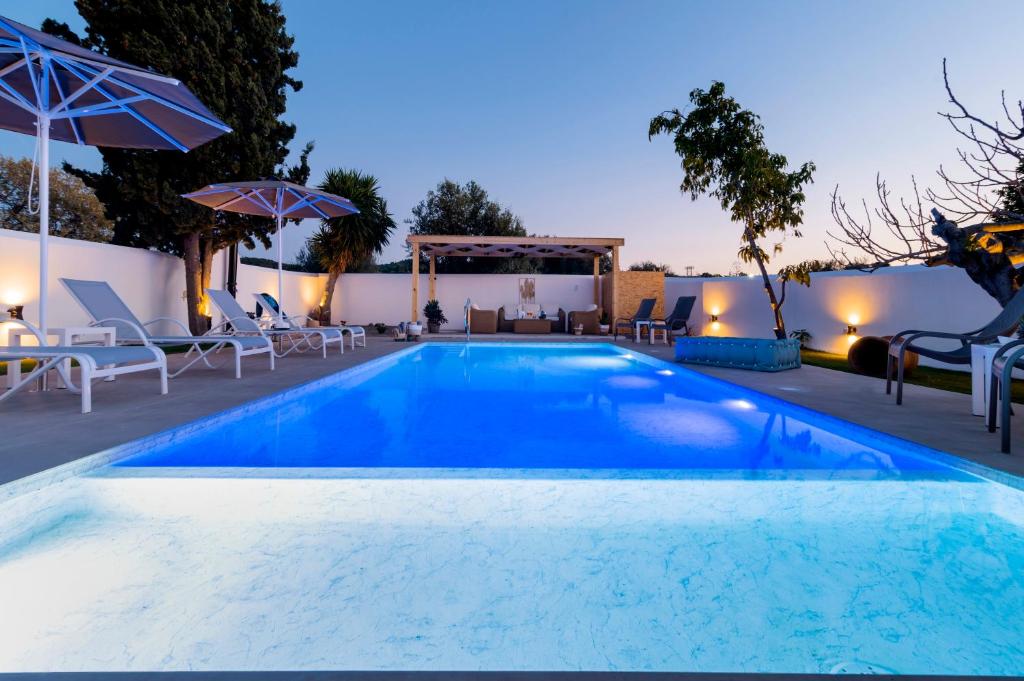 a pool with chairs and umbrellas at night at Villa Eleni in Soroni