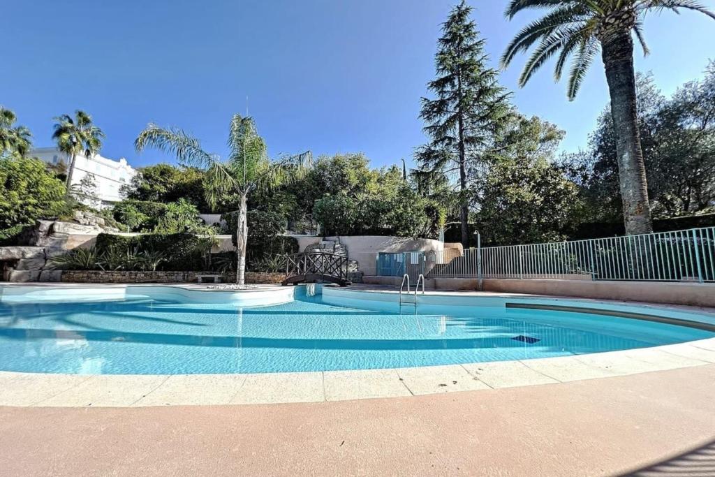 a swimming pool with blue water and palm trees at 3-room apartment in a high-end residence with swimming pool in Cannes