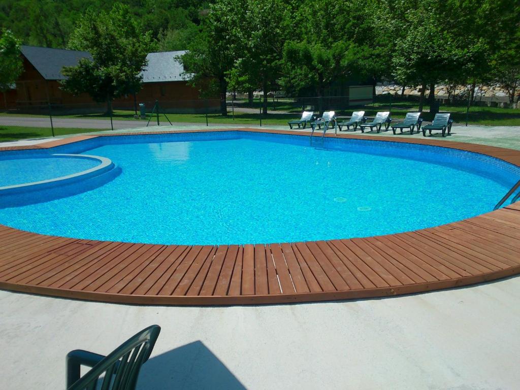 una gran piscina con una terraza de madera y sillas en Camping Prado Verde, en Vilamòs