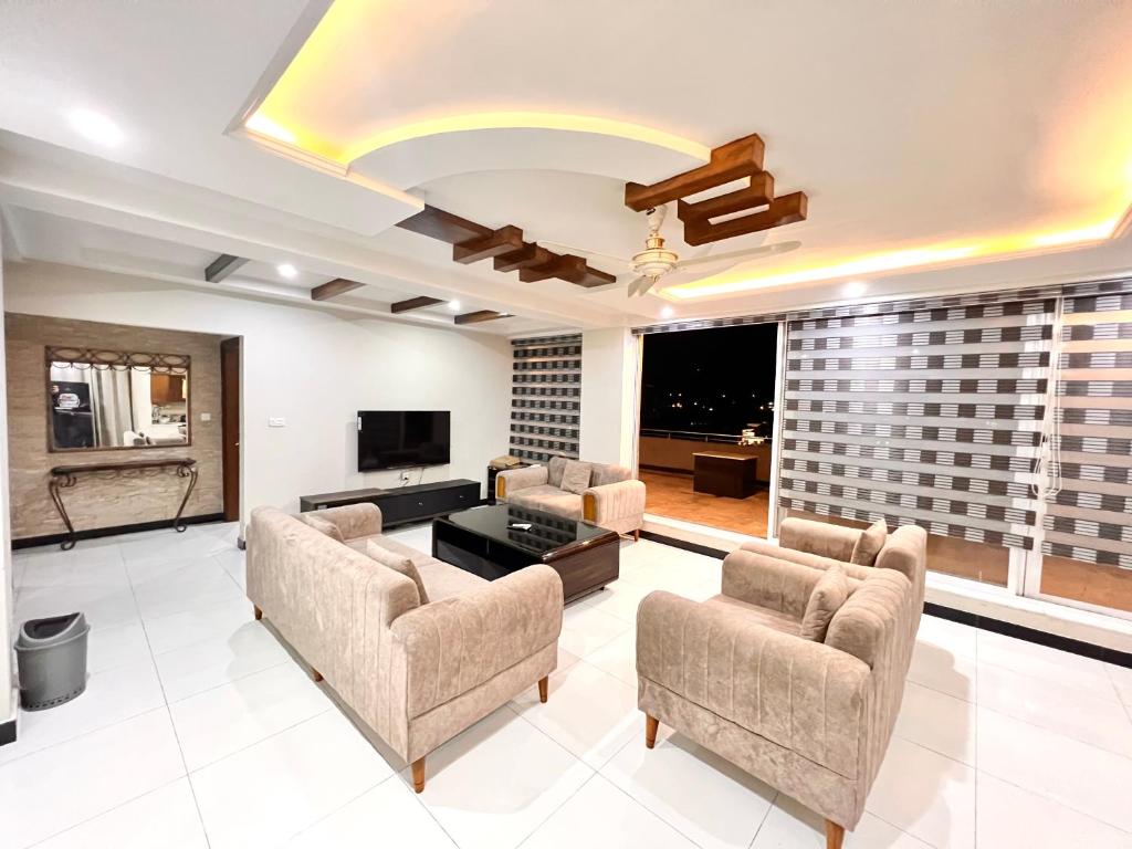 a living room with a couch and chairs and a tv at Luxury Apartment Hotel in Islamabad