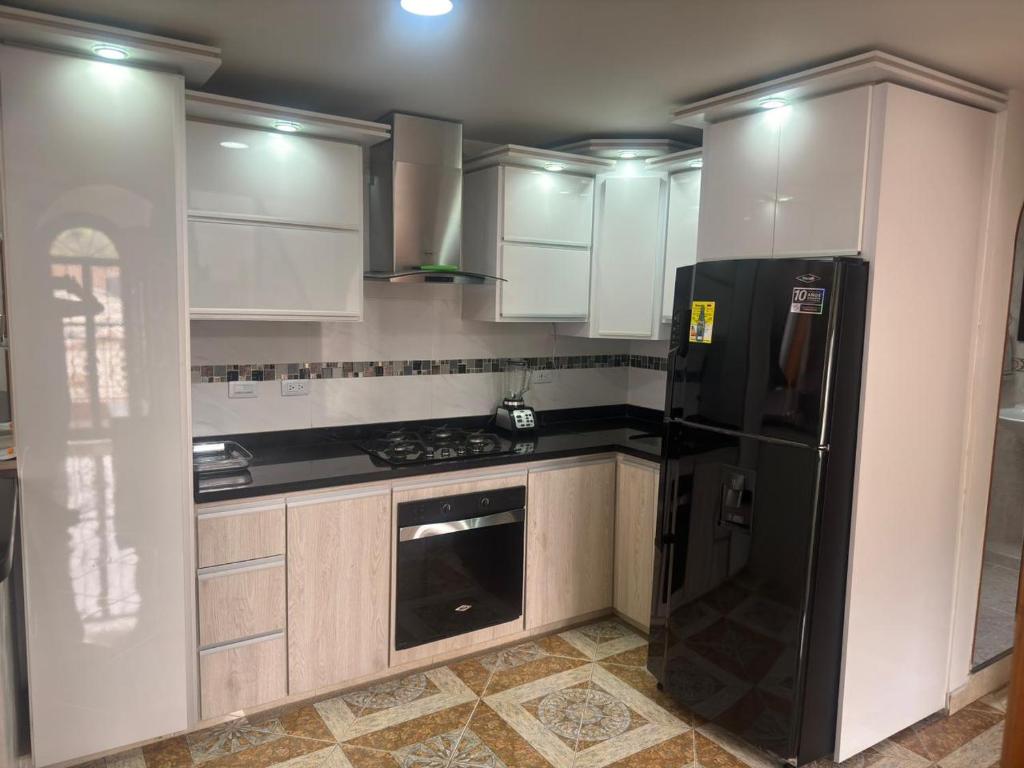 a kitchen with white cabinets and a black refrigerator at Apartamento La Hermosa in Santa Rosa de Cabal