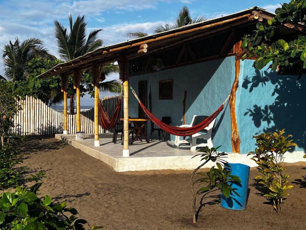 uma casa azul com uma rede em frente em Jardin Pacifico em Canoa