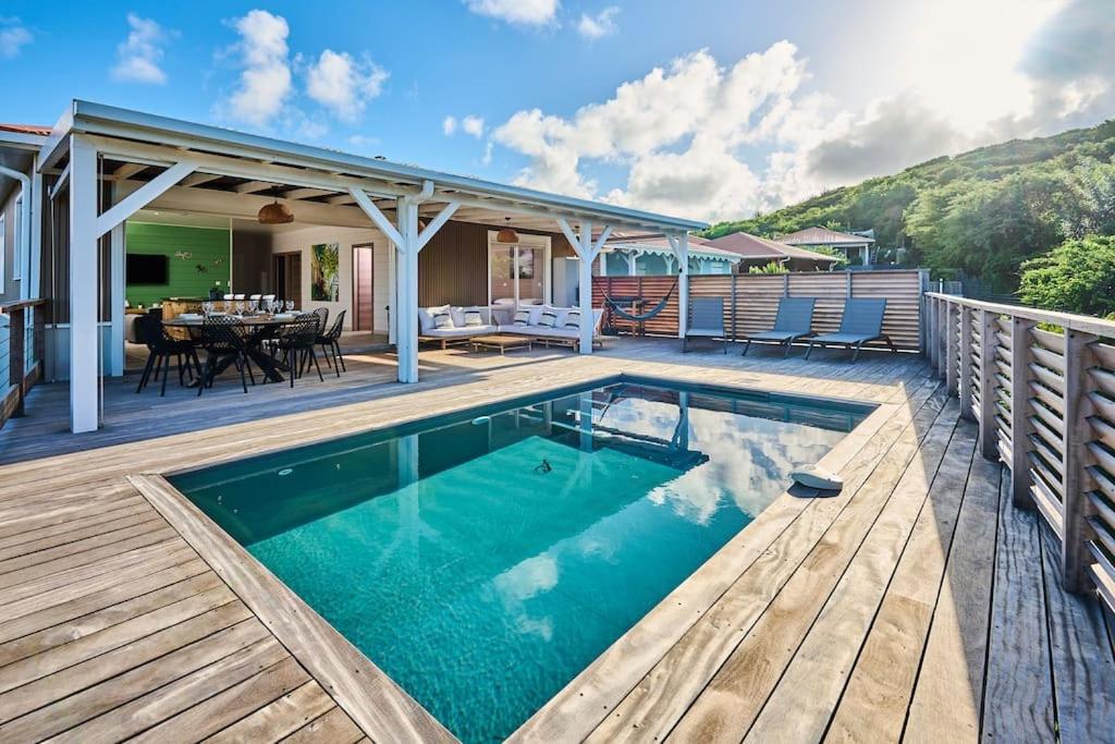 a swimming pool on a deck with a table and chairs at villa faula in Le Vauclin