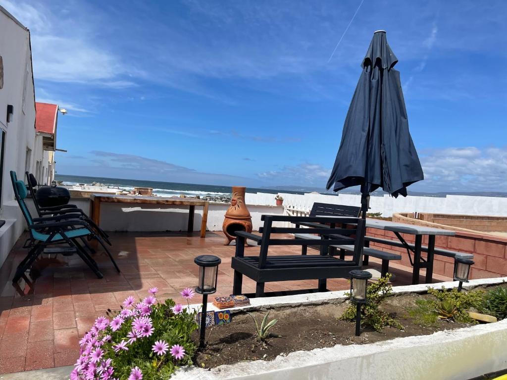 eine Terrasse mit einem Sonnenschirm, einem Tisch und Stühlen in der Unterkunft Baja Azul in Ensenada