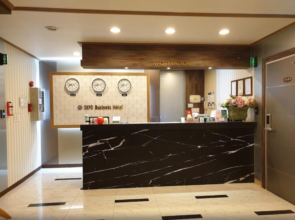a lobby with a counter with clocks on the wall at Okpo business hotel in Geoje