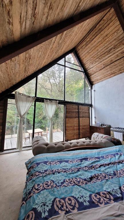 a large bed in a room with large windows at Cabaña privada in San Lucas Sacatepéquez