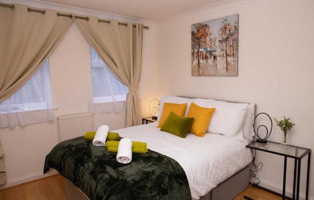 um quarto com uma cama com almofadas amarelas e verdes em The Green Lodge (Bush Hill Park) em Enfield
