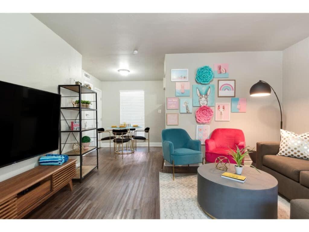 ein Wohnzimmer mit einem Sofa, einem TV und einem Tisch in der Unterkunft The Flamingo 102 l Pool I 65 Smart TV I Sleeps 5 in Austin