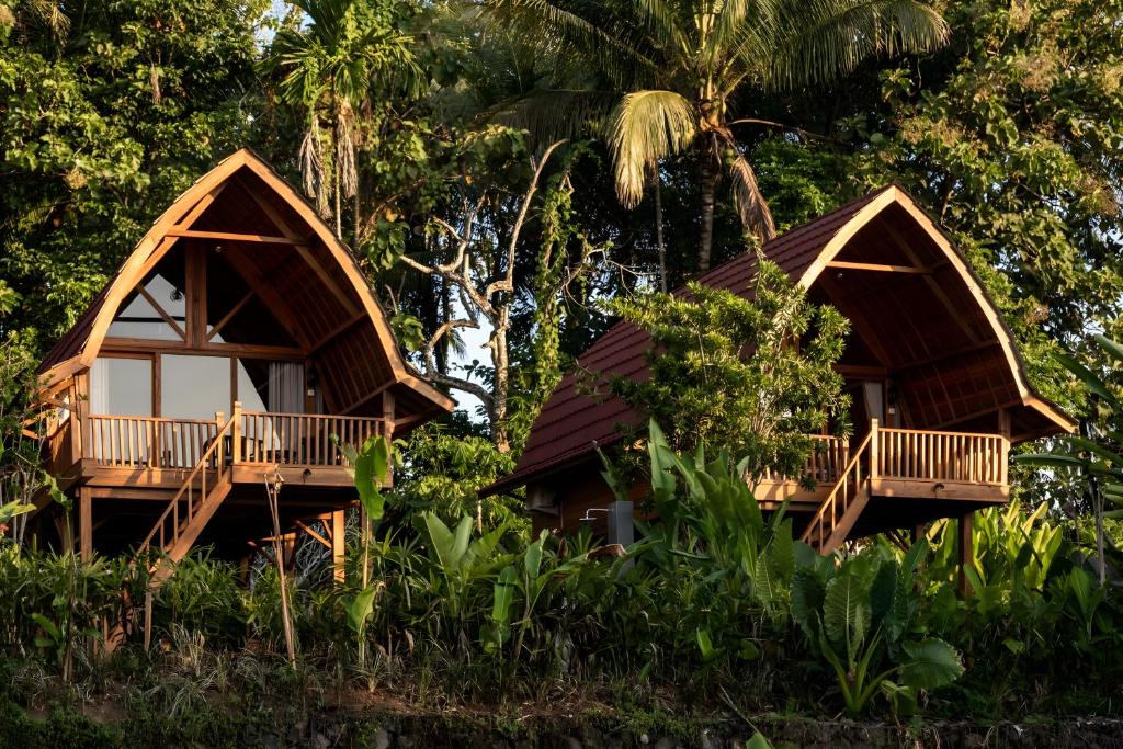 dos cabañas en el bosque con árboles en Kusfarm Bali en Selemadeg