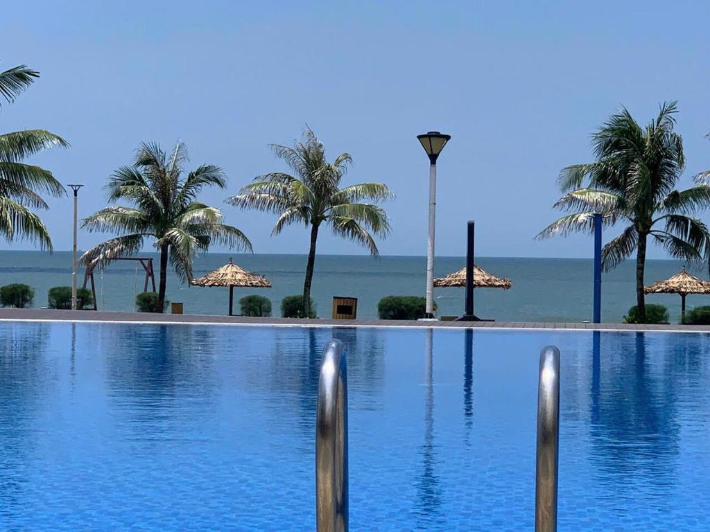 a swimming pool with palm trees and the ocean at BORACAY VILLA B1007 in Long Hai