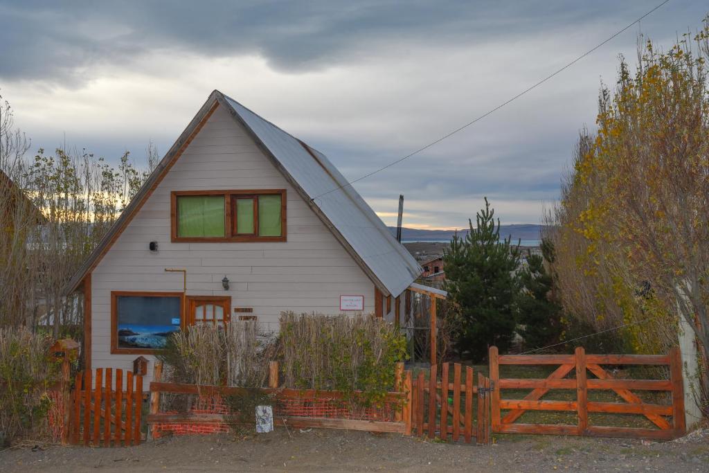 una pequeña casa blanca con una valla de madera en Casa de Lago y Montaña en El Calafate