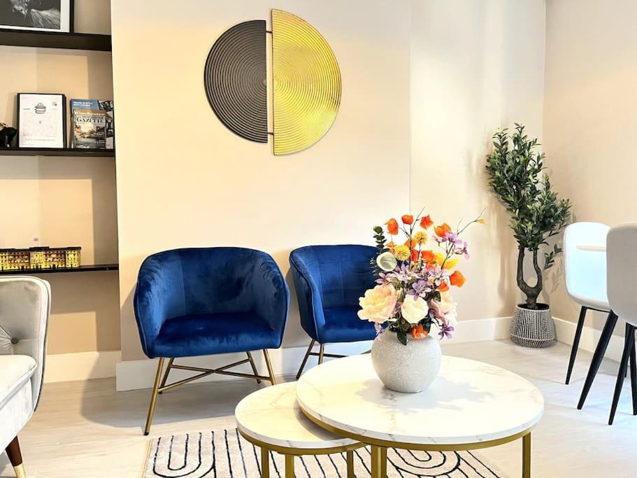 una sala de estar con 2 sillas azules y un jarrón con flores en Central Winchester Serviced Apartments, en Winchester
