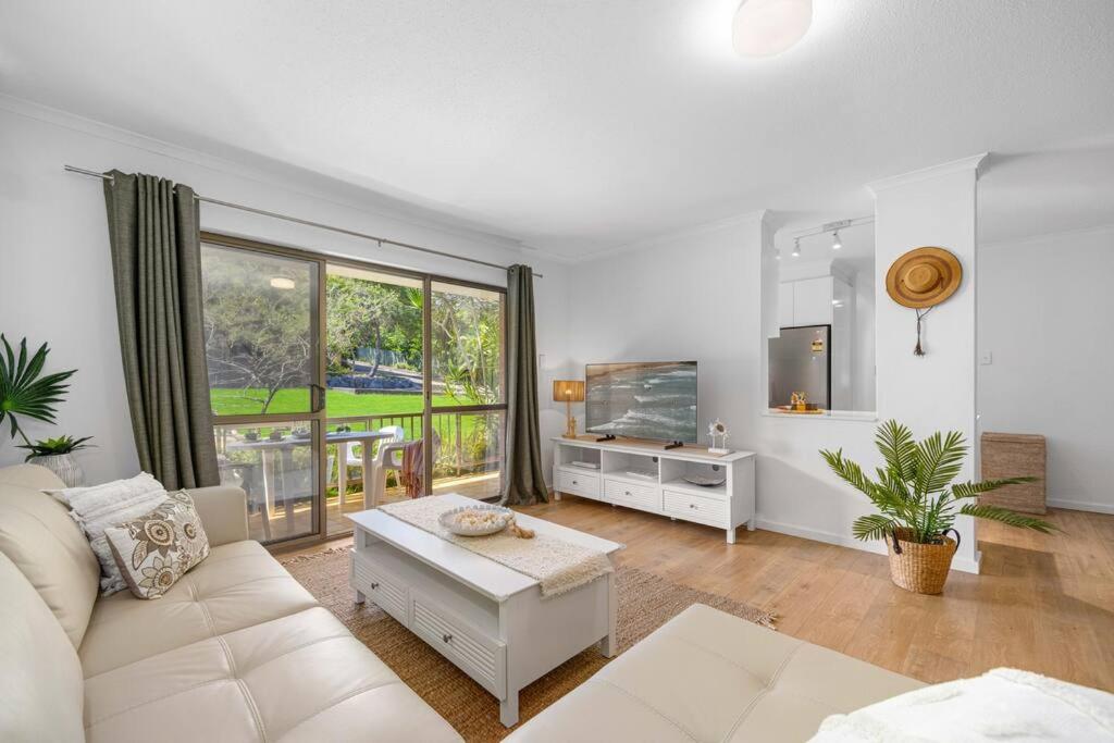 sala de estar con sofá blanco y TV en Shelly Cove Apt 12 - common pool, en Port Macquarie