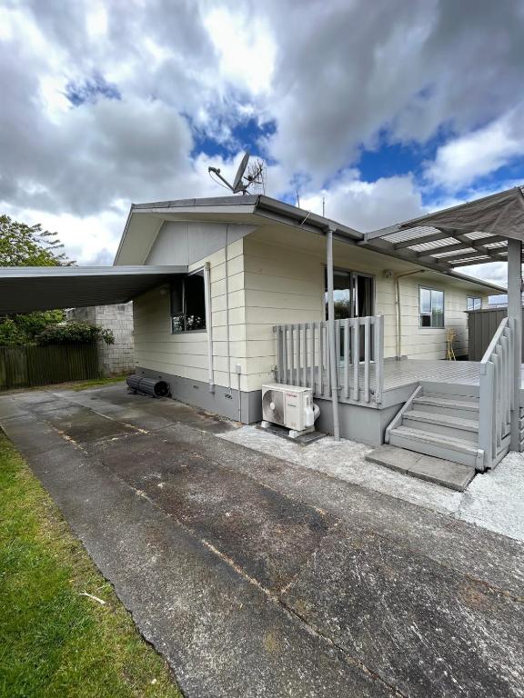 a small white house with a porch and stairs at Town Centre Retreat in Taupo