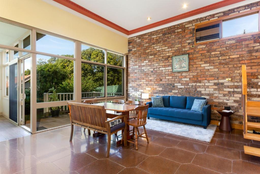 uma sala de estar com uma mesa e um sofá azul em Spacious 3-Bed Mid Century Home Near CBD em Sydney