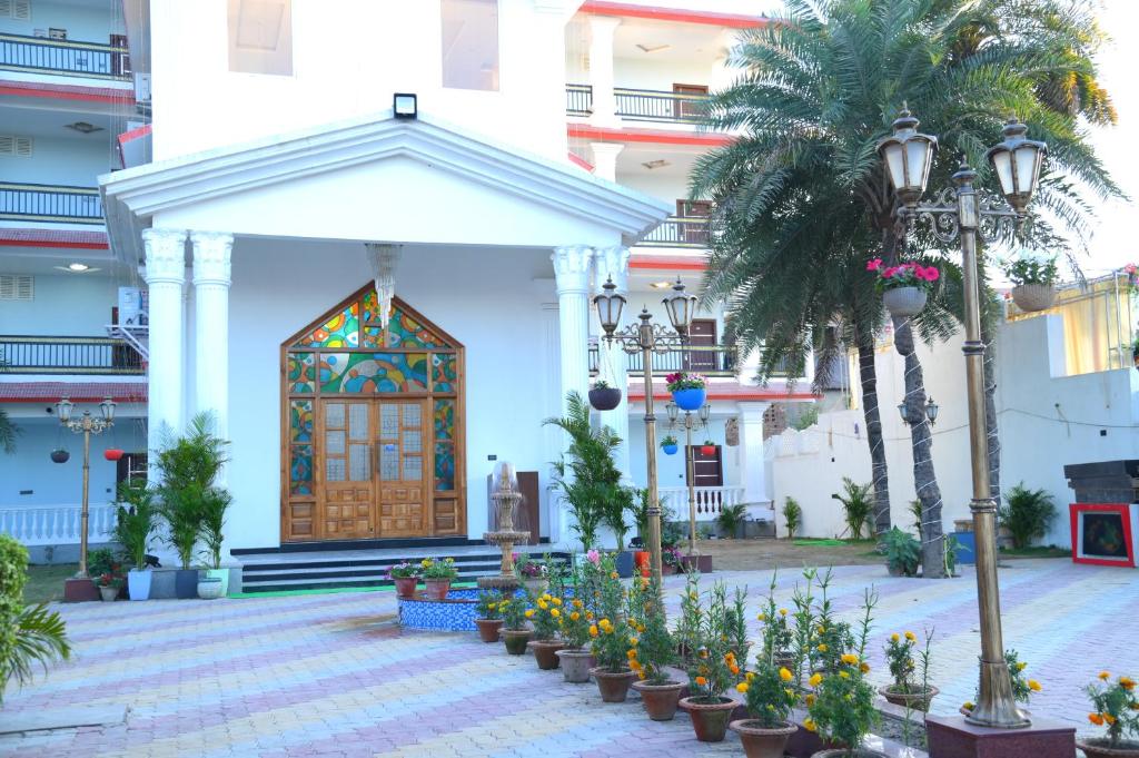 a front entrance to a building with flowers and palm trees at Hotel Harsh Garden in Begusarai