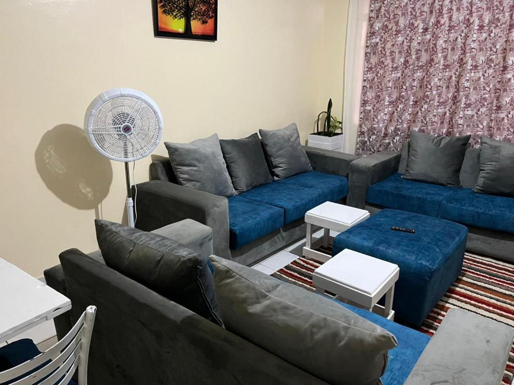 a living room with blue couches and a fan at Machakos Town Coffee Residencies in Machakos