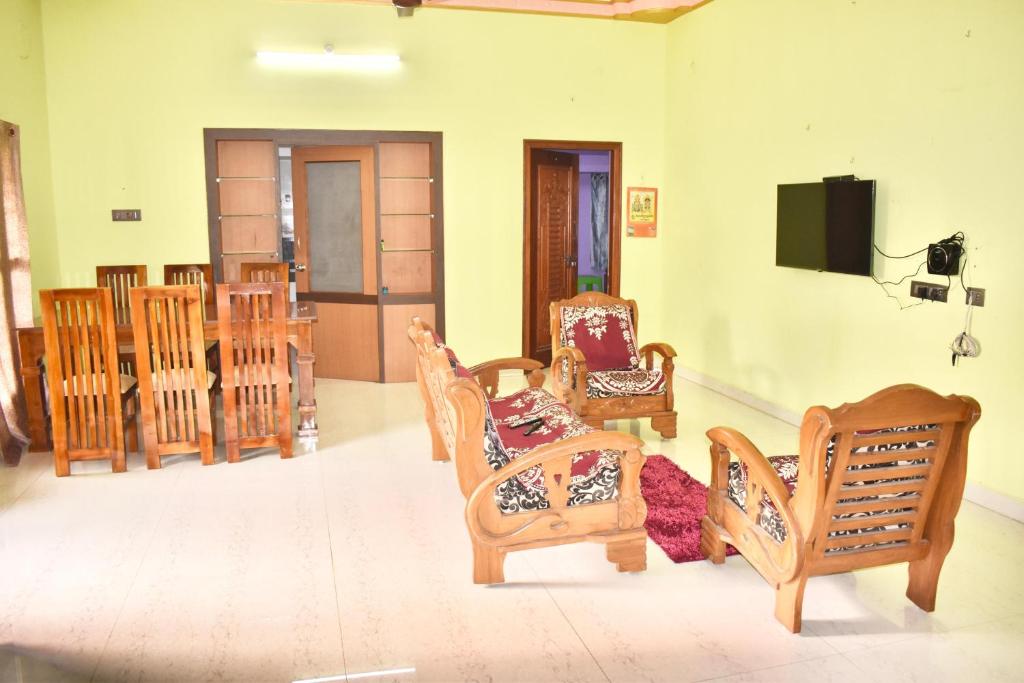 a living room with wooden chairs and a tv at Sri Annamalaiyar Guest House in Tiruvannāmalai