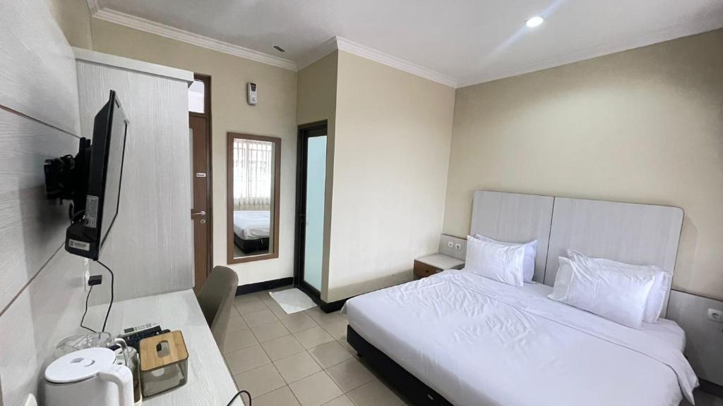 una camera d'albergo con un letto e una televisione di tekMIRA Hotel a Bandung