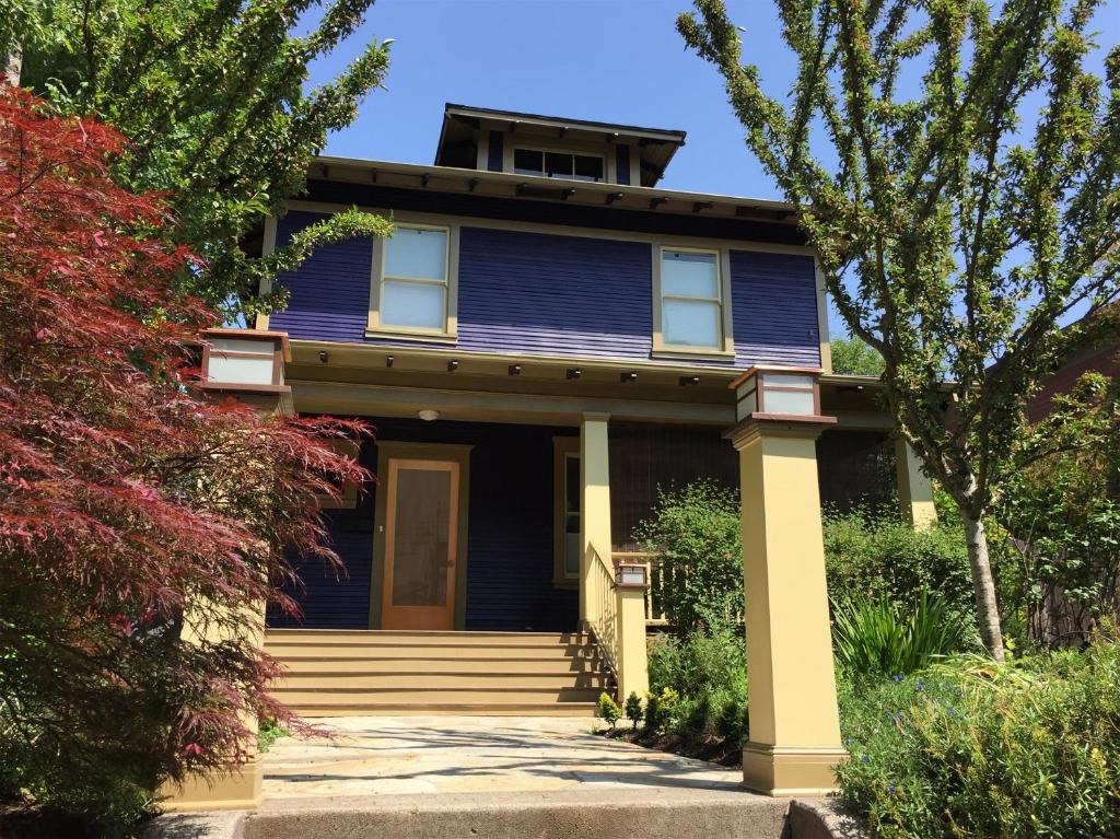 a blue house with a front porch and trees at Big beautiful house off Alberta—2 bdms sunny patio in Portland