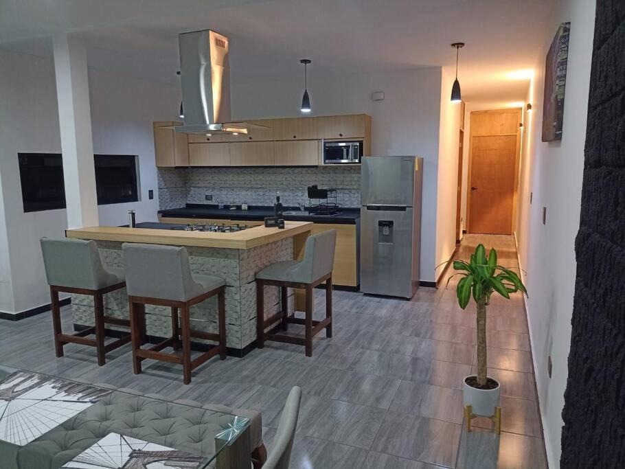 a kitchen with a island with chairs and a counter at Máster Suite Departamento cerca de Isla San Marcos in Aguascalientes