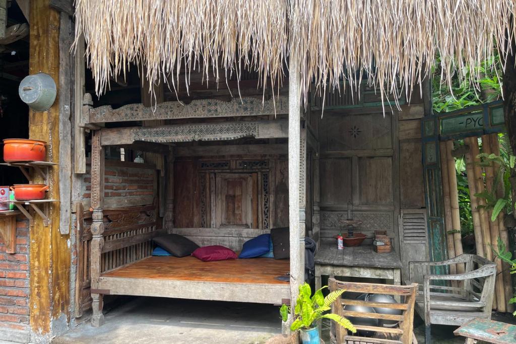 金巴蘭的住宿－TwoSpaces Living at Bunga Desa, Jimbaran，茅草屋顶小屋内的木床