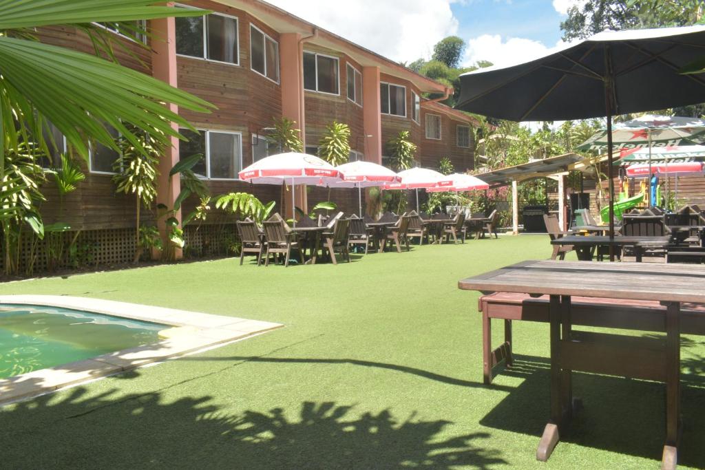 an outdoor patio with tables and chairs and umbrellas at Pacific Gardens Hotel in Goroka