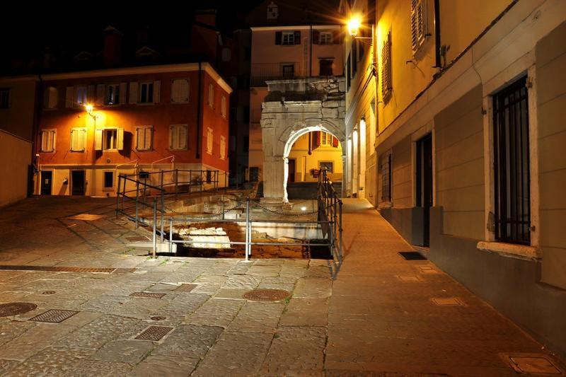 an alley with an arch in a city at night at Barbacan Boutique Hotel in Trieste