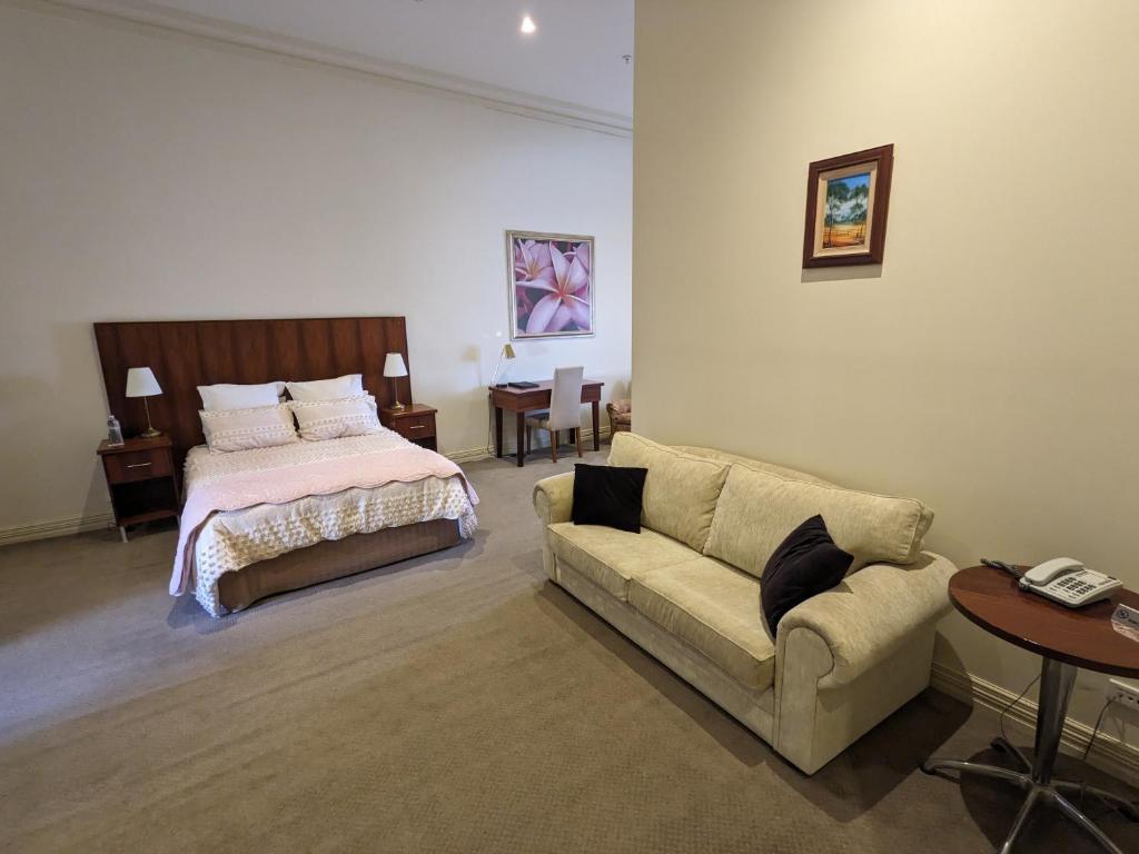 a bedroom with a bed and a couch and a table at The Astra Broken Hill in Broken Hill