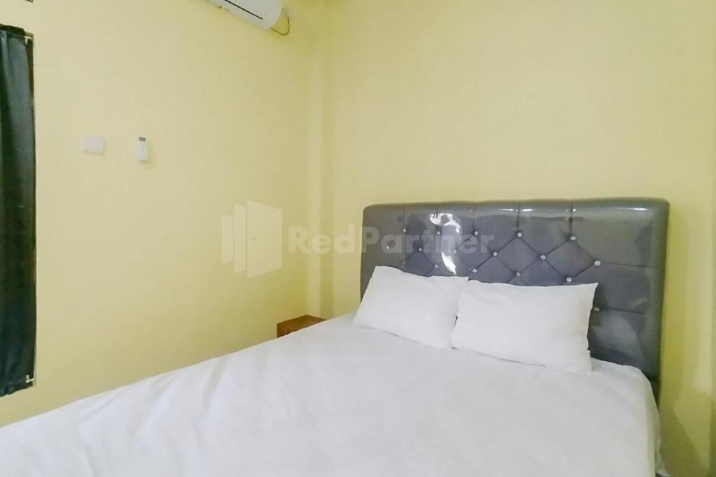1 dormitorio con 1 cama grande con sábanas blancas en Asyura Kostel Syariah Redpartner, en Kedaton