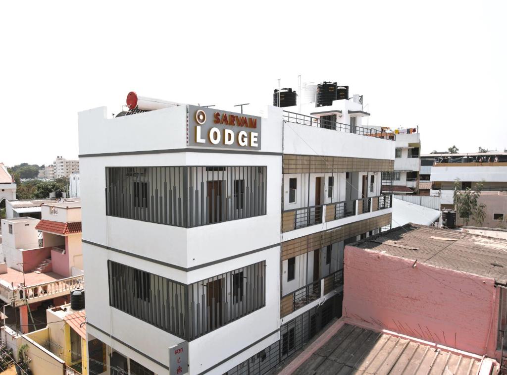 a white building with a sign on top of it at Sarvam Lodge in Pīlamedu