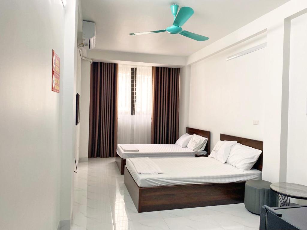 two beds in a room with a ceiling fan at GRAD Minh Trang Motel in Hanoi