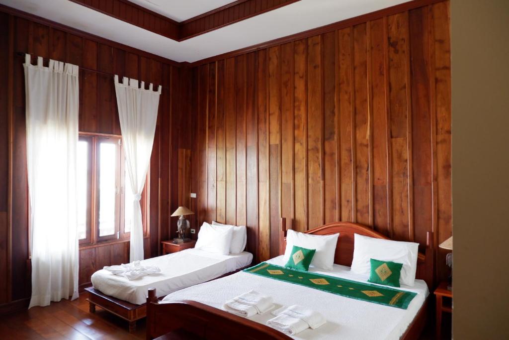 Muang Không的住宿－Kongmany Prestige Hotel，一间卧室设有两张床和木墙