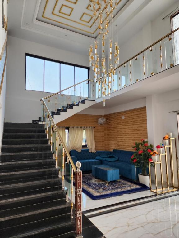 a living room with a staircase and a blue couch at Manidweepa farm house in Venkatāpur