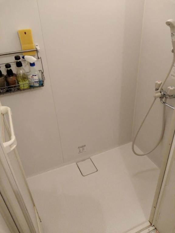 a white bathroom with a shower with a hose at Hashibaya TABI-NE in Kanazawa