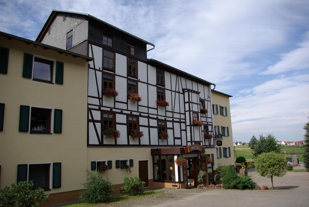 un grand bâtiment avec des plantes en pot dans l'établissement Hotel in der Mühle, à Werdau