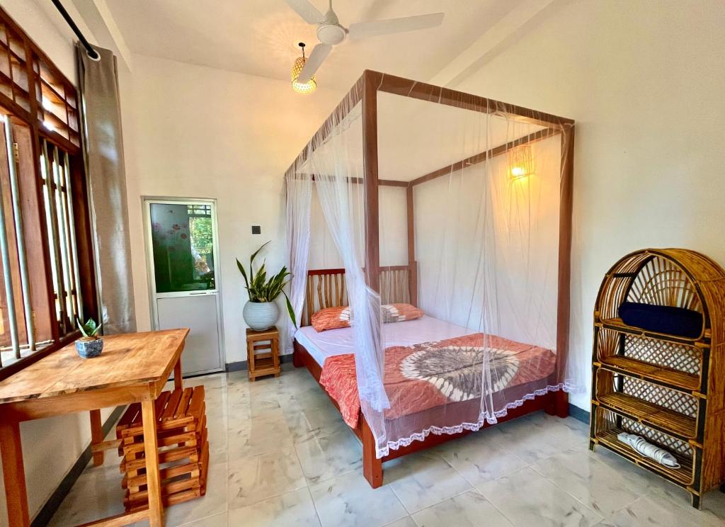 una camera con letto a baldacchino e scrivania in legno di The Window a Matara