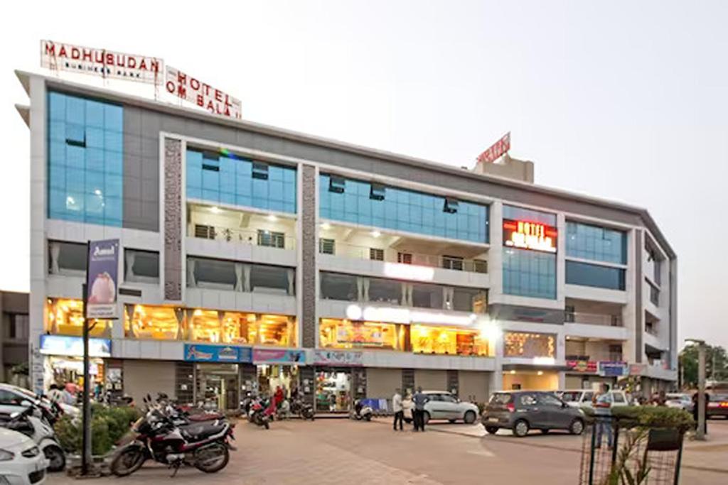 un gran edificio con coches estacionados en un estacionamiento en Hotel Om Balaji en Ahmedabad