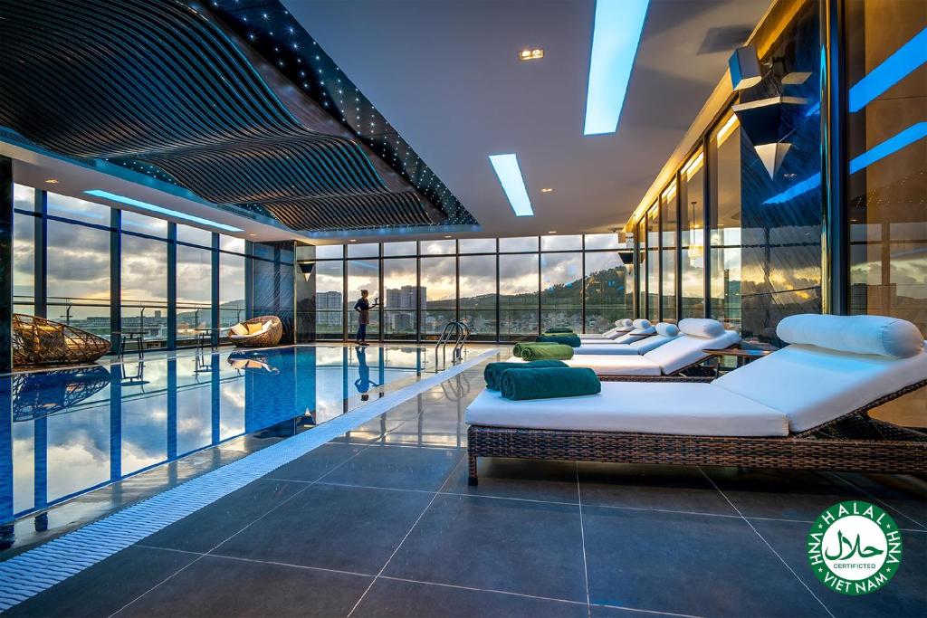 two beds in a room with a swimming pool at DeLaSea Ha Long Hotel - Modern Bayview Escape in Ha Long