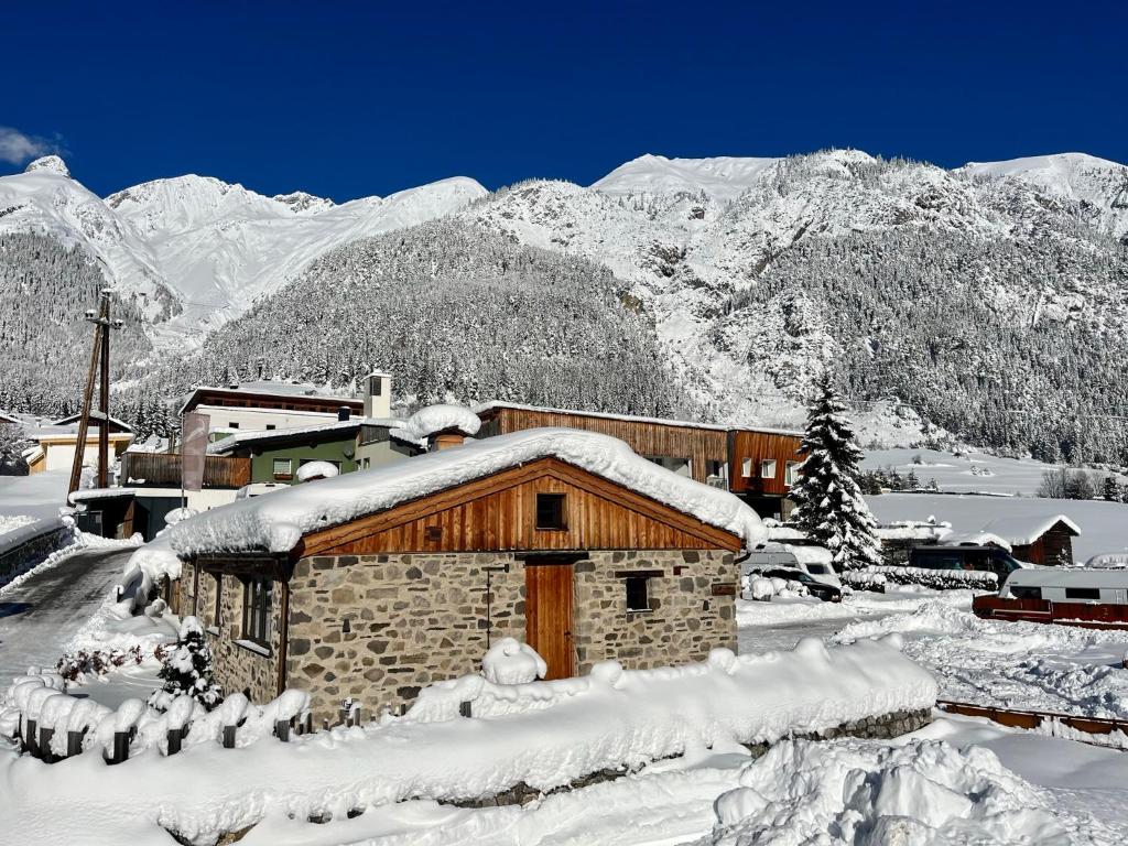 un edificio cubierto de nieve frente a una montaña en ArlBerglife Ferienresort, en Pettneu am Arlberg