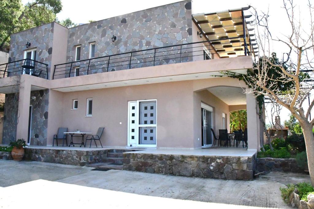 a house with a balcony and a patio at Sanctuary Villa in Vagia, Aegina in Agia Marina Aegina