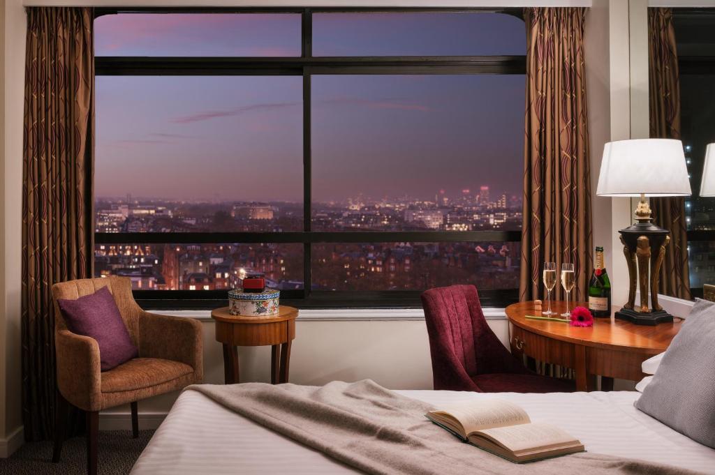 una camera da letto con una grande finestra con vista sulla città di Millennium Hotel London Knightsbridge a Londra