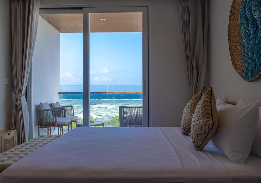 a bedroom with a bed and a view of the ocean at Stone Beach Club in Dhiffushi