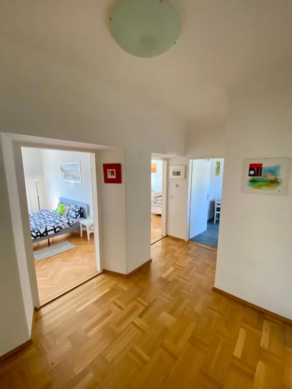 una sala de estar con suelo de madera y una habitación con cama en City Retreat in Eisenstadt Zentrum, en Eisenstadt