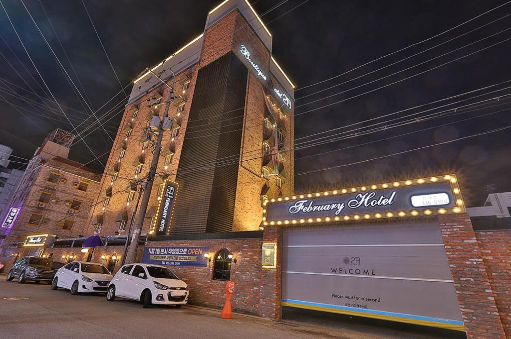 February Hotel Gimhae في Gimhae: سيارتين بيض متوقفتين امام مبنى