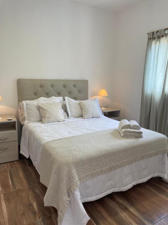 1 dormitorio con 1 cama grande con sábanas blancas en Los 4 elementos en San Marcos Sierras