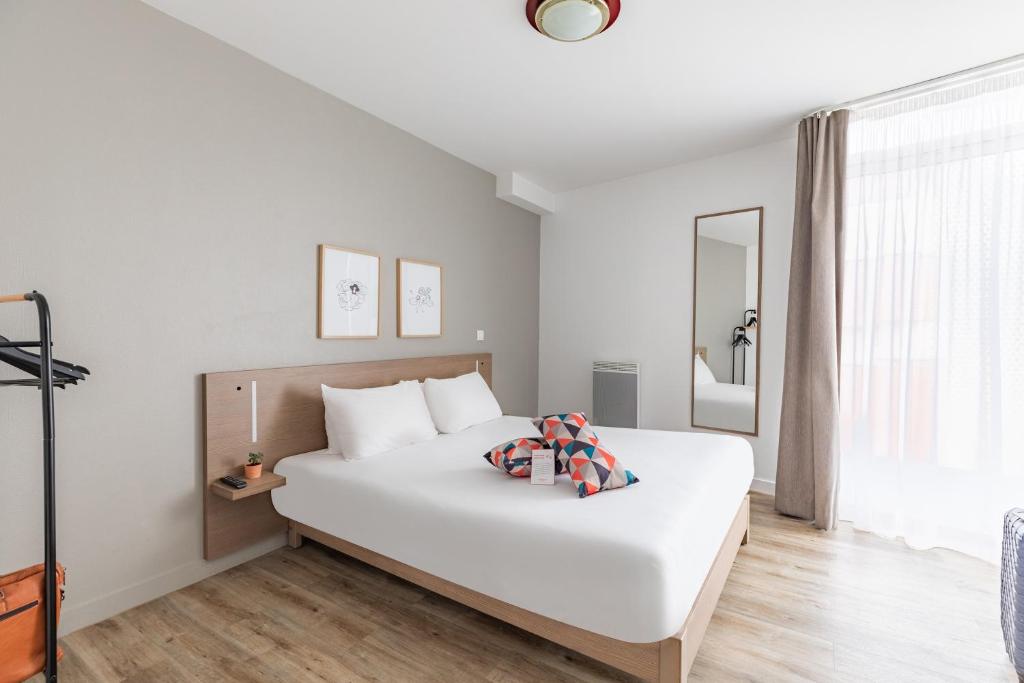 a white bedroom with a large white bed and a window at Appart'City Confort Le Mans Centre in Le Mans